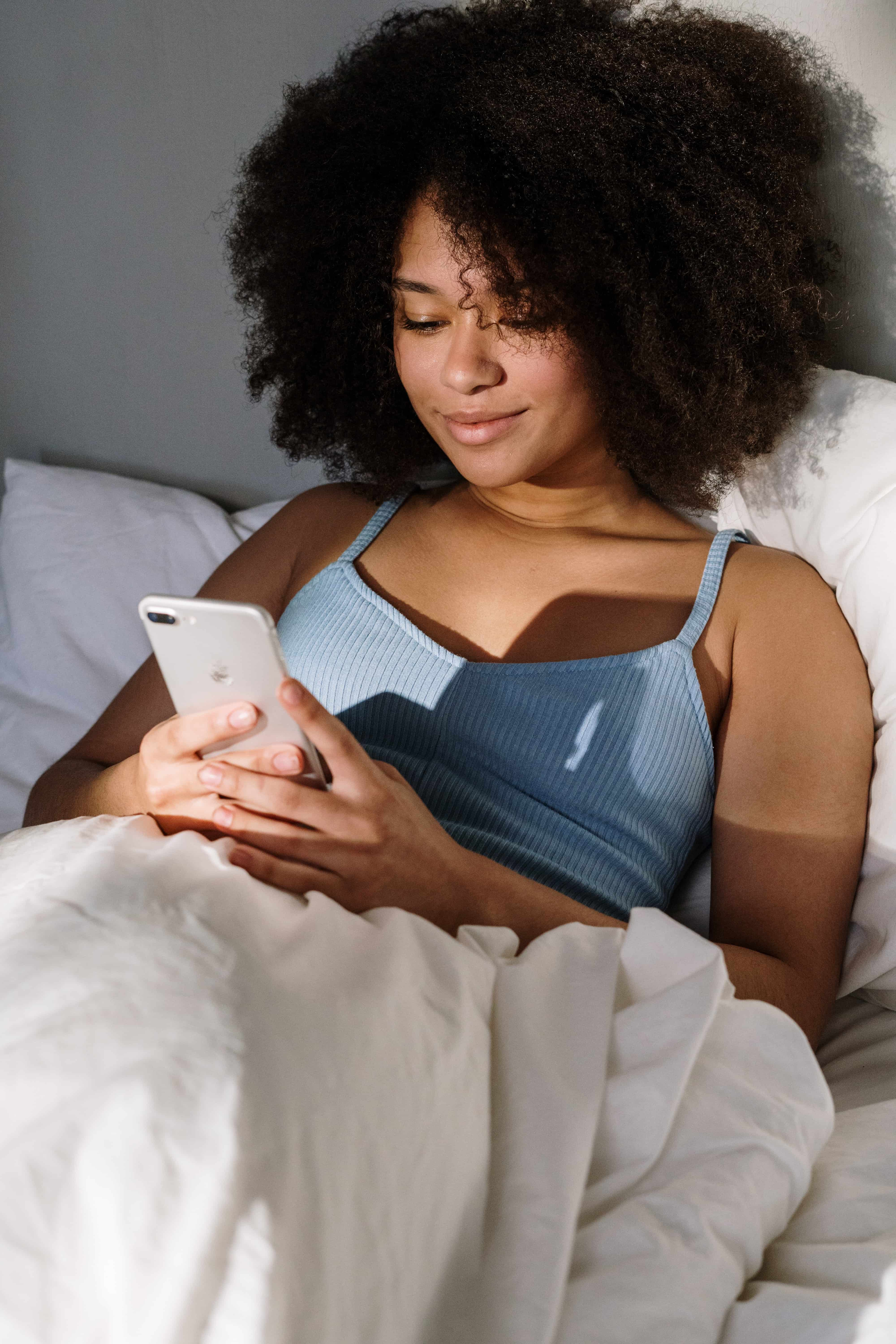 femme sur son téléphone dans son lit