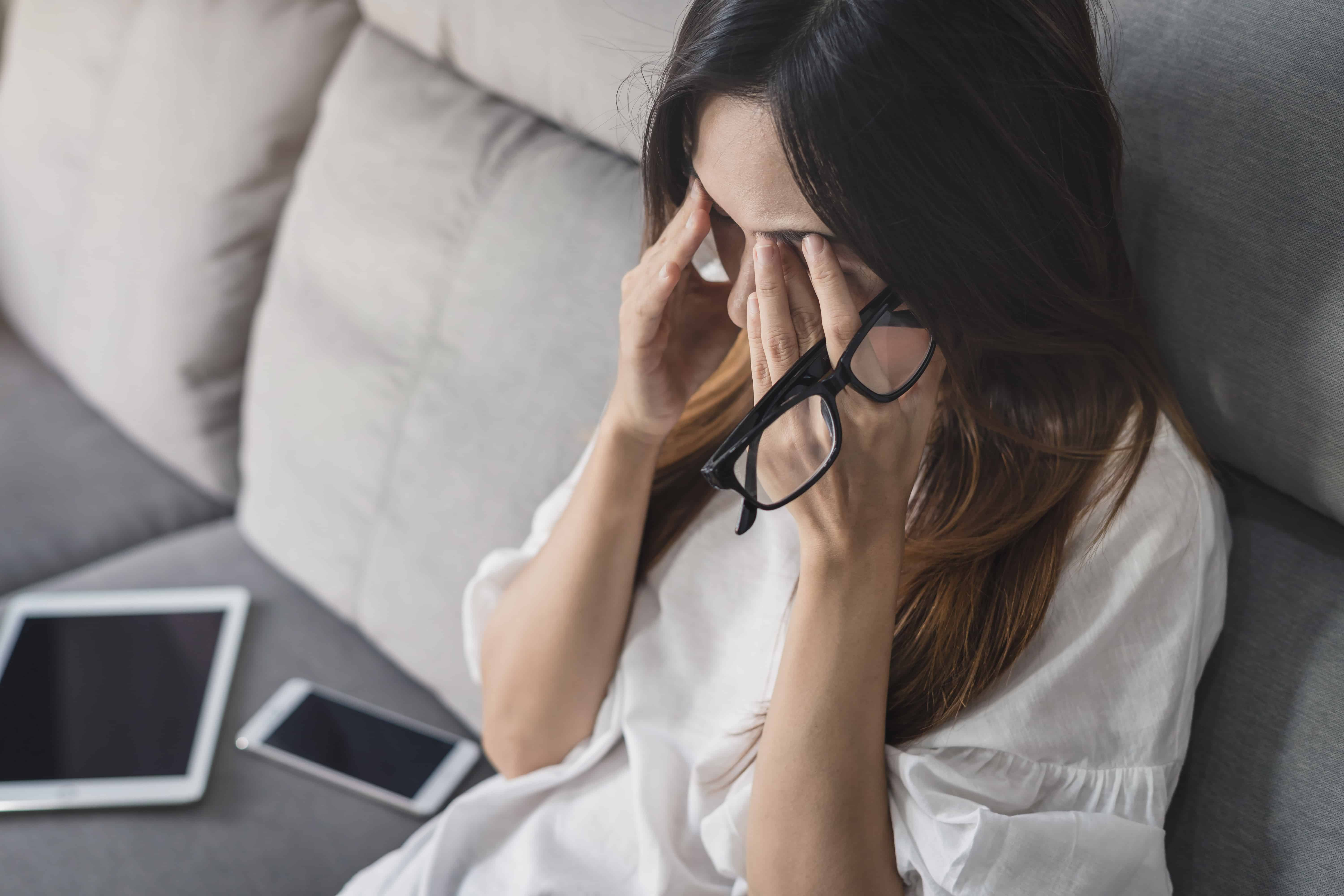 femme qui tiens sa tête avec ses lunettes dans ses mains